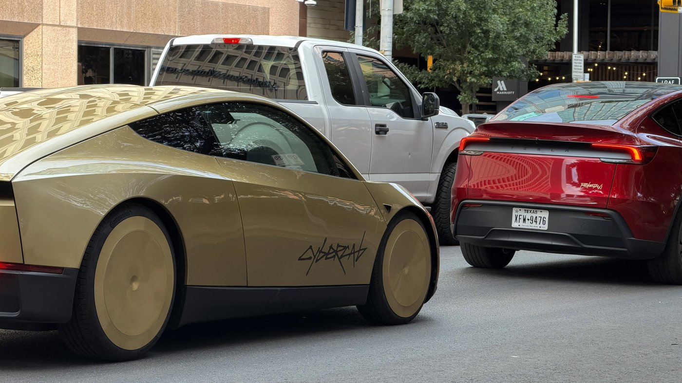 A gold Tesla Cybercab beside a red Tesla Model Y with Texas plates on an Austin street