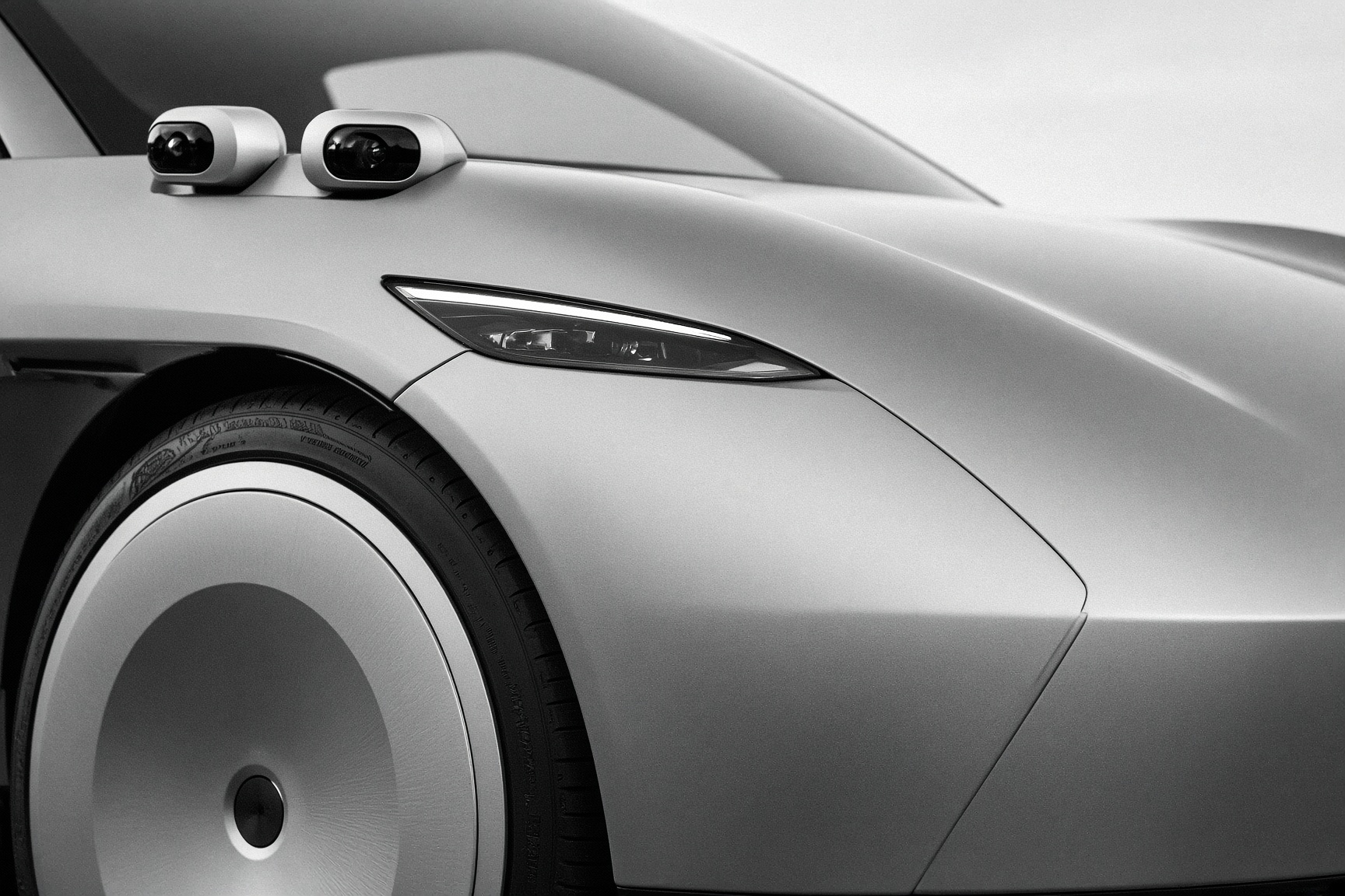 Detail of a Cybercab nose and hubcap in hard light.