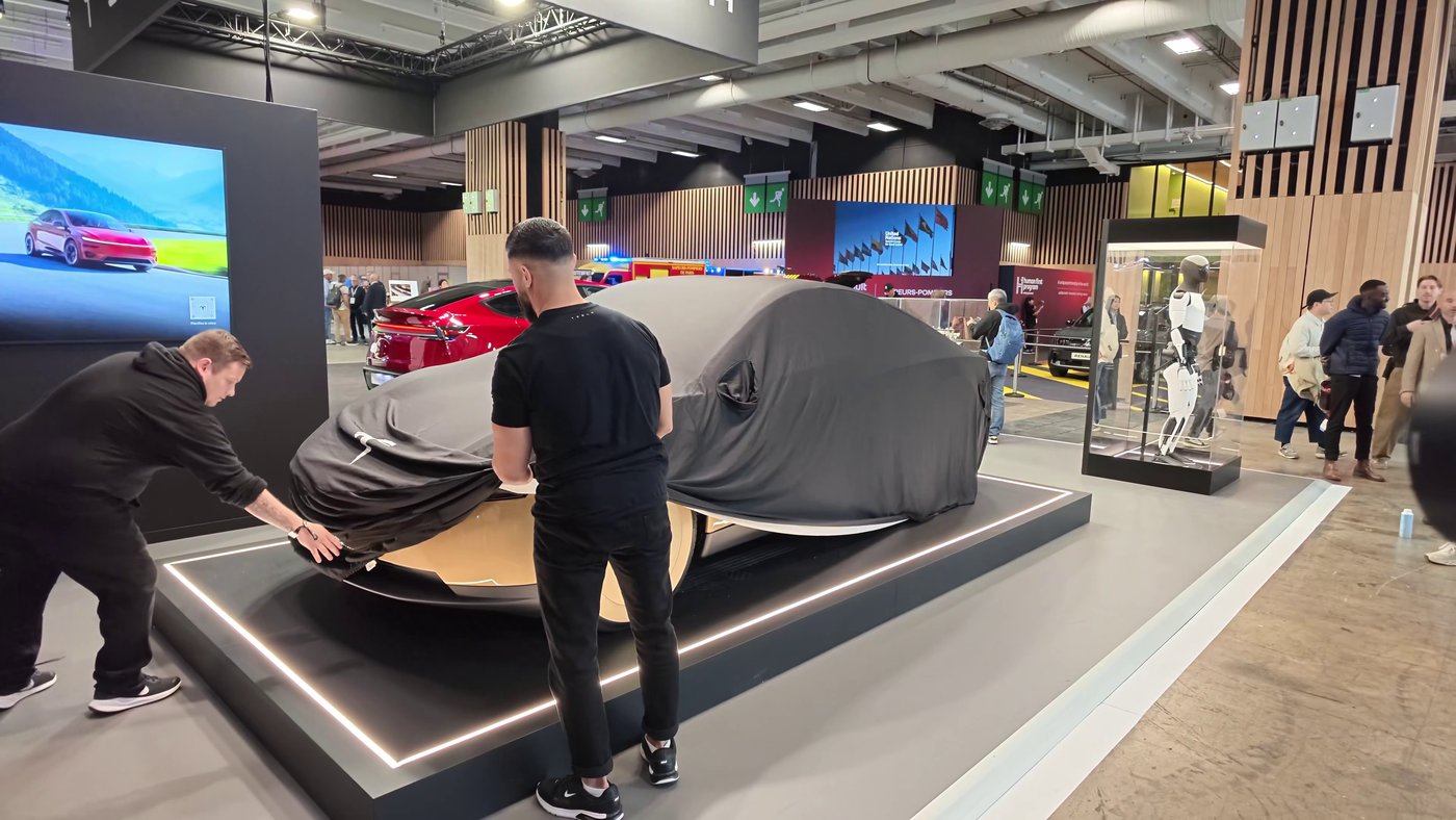 Tesla crew peel the cover off the Cybercab on stand C25 on press day. Photo via @DavidMoss / X